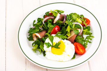 Fresh vegetable salad with ham and fried egg