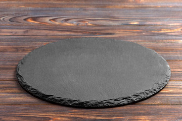 Slate plate on table. black slate stone on wooden background. copy space