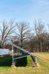 Naklejka na ściany i meble Blue solar panels in photovoltaics power station farm with trees in background, future innovation energy concept, clear blue sky background, Czech Republic