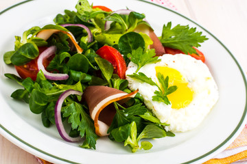Fresh vegetable salad with ham and fried egg