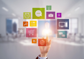 Modern office interior and close of businesswoman hand choosing icon on multimedia interface