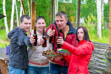 Young friends on the nature on a picnic with a shish kebab and beer have a rest