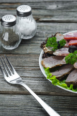nicely sliced meat on plate, on wooden background in rustic style