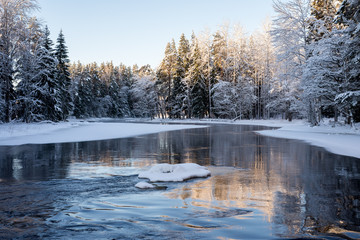 Sunrise river in a cold winter landscape with snow and frost.