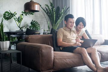 Happy Asian couple looking at the computer together at home.