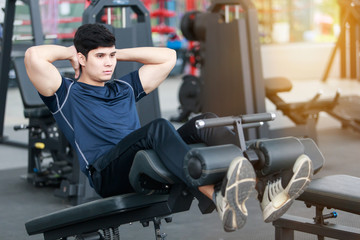 Asian sport man doing sit-ups on the floor in gym. man exercising in fitness gym for good health. Athletic young man exercising equipment at gym, workout in fitness center.