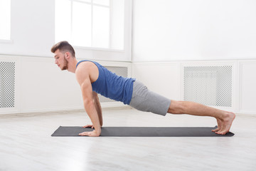 Fototapeta na wymiar Man training plank at white background indoors