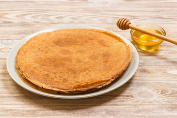 Pancakes with honey and butter on a wooden background