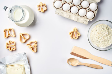 Objects and ingredients for baking, plastic molds for cookies on a white background. Flour, eggs, milk, butter, cream. Top view, space for text