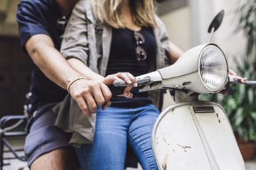 Obraz premium Loving couple riding an old scooter. The woman is sitting in front of him, the man teaches her how to drive