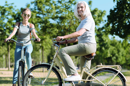 Active sport. Joyful positive aged woman riding a bike and smiling while leading healthy lifestyle