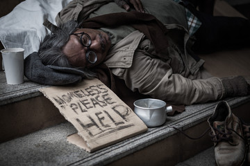 Potrait of homeless people sleeping with help papaer sign