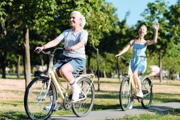 Healthy lifestyle. Delighted positive elderly woman riding a bike and being in a positive mood while leading healthy lifestyle
