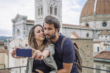 Loving couple taking a selfie in front of the church Santa Maria del Fiore, Florence Cathedral