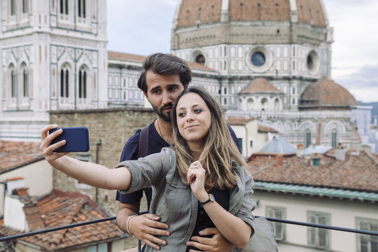 Loving couple taking a selfie in front of the church Santa Maria del Fiore, Florence Cathedral