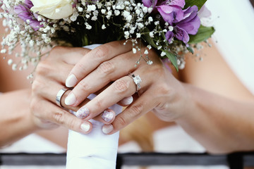 Obraz na płótnie Canvas Bride holding wedding bouquet showing wedding rings