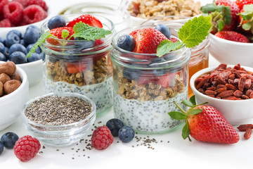 Breakfast in a jar, chia with berries and oat flakes and ingredients on white table