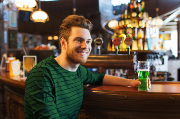 man drinking green beer at bar or pub