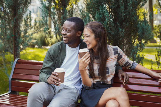 Multiethnic couple in love having coffee in park