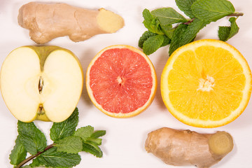 A vitamin set on a white background fruit and citrus apples grapefruit orange ginger mint and blander Healthy eating glass of juice