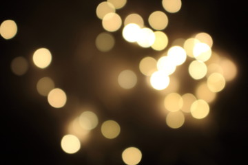 Festive golden blurred lights. Shiny bokeh. Abstract defocused lights. Glowing effect concept. Blur lights in dark night. Illuminated decoration background. 