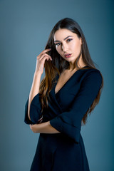 Fototapeta premium Young beautiful sexy girl in black dress on blue grey background.