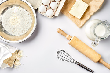 Preparation of the dough. A measurement of the amount of ingredients in the recipe. Ingredients for the dough: flour, eggs, rolling pin, whisk, milk, butter, cream. Top view, space for text