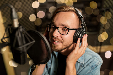 man with headphones singing at recording studio