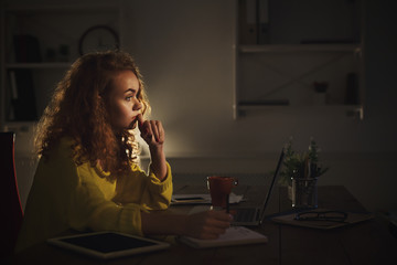 Thoughtful woman making notes at home in the evening