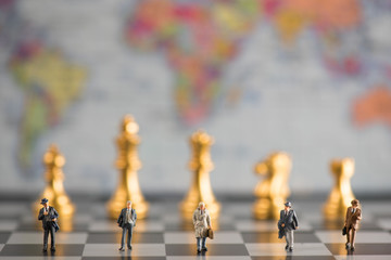 group of miniature businessmen walking in the chess board with the background is world map illustrate  business and leadership concept