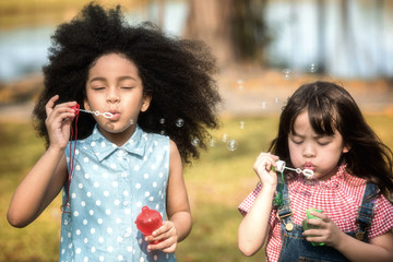 Children are happy to play blow soap bubbles in the garden. Soft focus concept.
