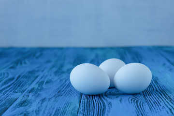 White eggs on blue background. Space for text
