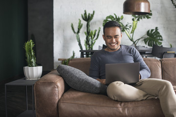 Asian man looking at the computer at home.