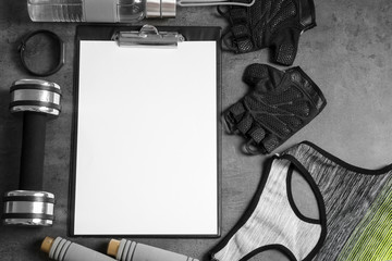 Clipboard with blank paper for exercise plan and gym stuff on grey background. Flat lay composition