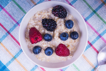 Oatmeal porridge with berries on a rustic napkin - top view
