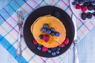 rural breakfast - tea and pancakes with berries and honey - top view