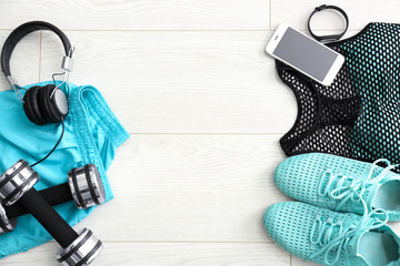 Gym stuff, mobile phone and blank space for exercise plan on wooden background. Flat lay composition