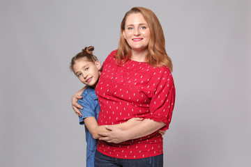 Portrait of happy mother and daughter on grey background