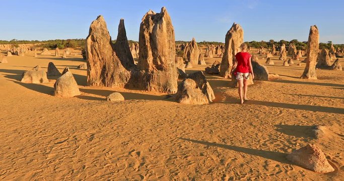 Western Australia travel discovery concept. Traveler woman walks through Pinnacles Desert, Nambung National Park, Cervantes. Female walking among limestone formations, WA