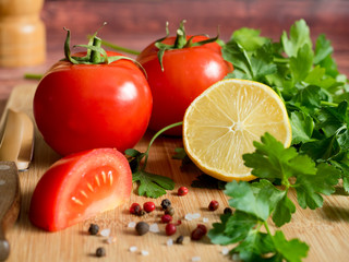 Fresh vegetables Tomatoes Lemon Parsley Pepper coarse Salt on a cutting Board