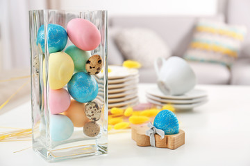 Glass vase with colorful Easter eggs on table