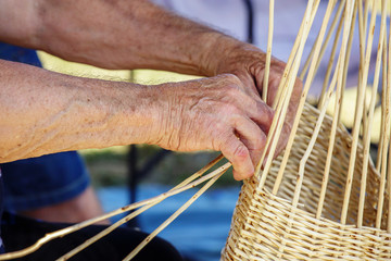 Man's hands making a wicker basket under sunny day