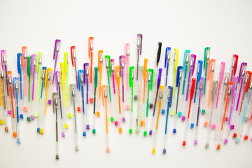Bright, colorful pens on a white background shot overhead. - Powered by Adobe