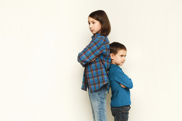 Small girl and her brother standing back to back