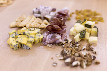 Different kinds of cheese, cheese biscuits and jamon on a wooden background