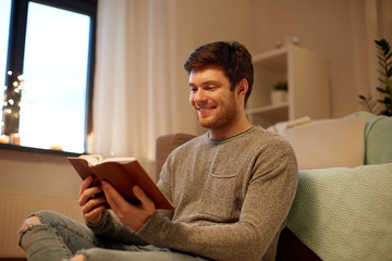 happy young man reading book at home