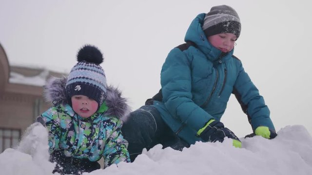 Children playing on a snowy mountain, throwing snow and smejutsja . Sunny frosty day. Fun and games in the fresh air.