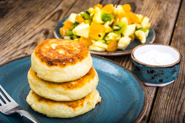 Hot delicious curd pancakes with fruit salad and yogurt