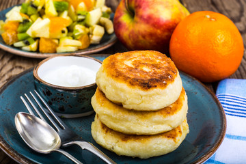 Hot delicious curd pancakes with fruit salad and yogurt