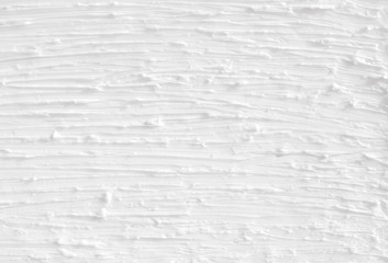 Texture of white paint on the wall. A background with continuous lines painted with brushes, handmade.